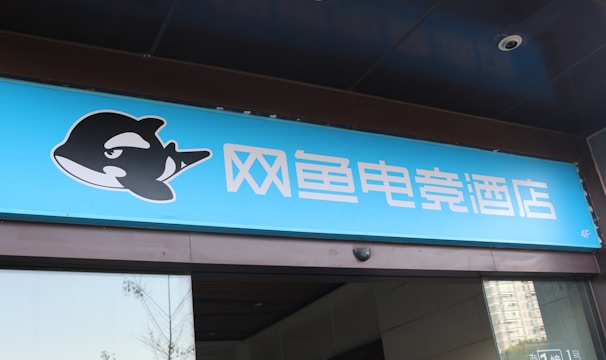 A building entrance features a vibrant blue sign with white Chinese characters and a stylized orca logo in black and white. The overall appearance suggests an establishment focused on eSports or digital activities.
